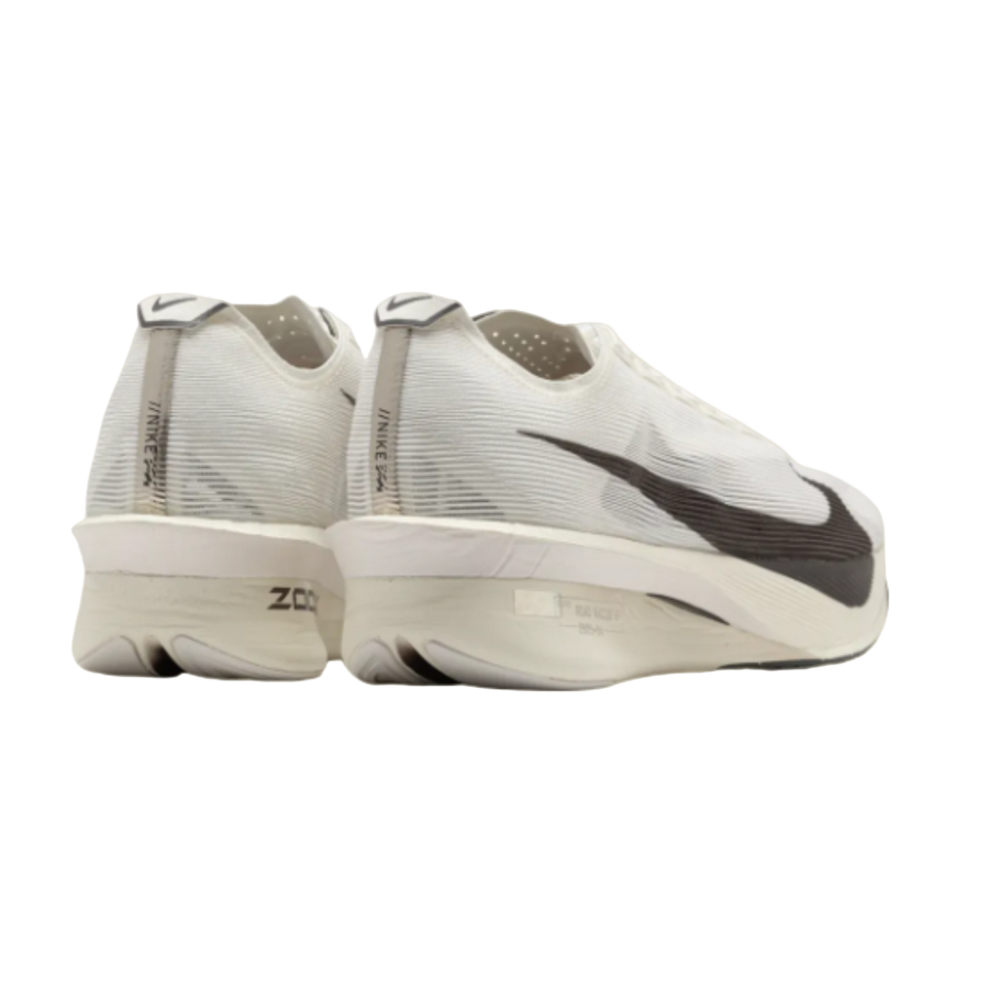 White running shoes with black swoosh logo on a beige background